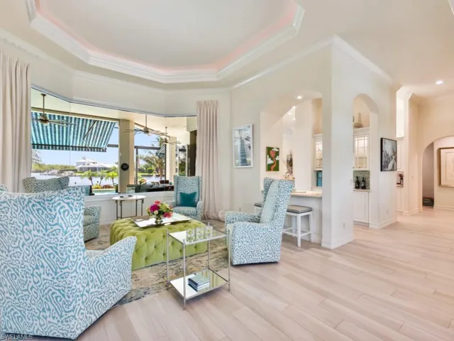 Living room featuring wood-type flooring, a raised ceiling, and crown molding