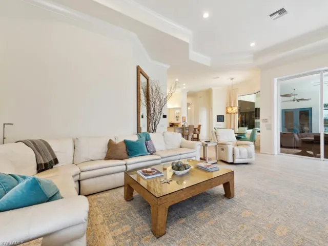 Living room featuring a raised ceiling, ornamental molding, and ceiling fan
