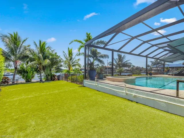 View of pool featuring glass enclosure and a lawn
