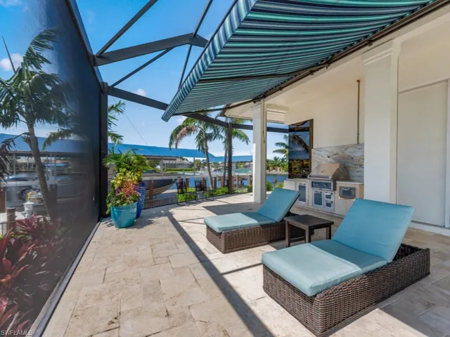 View of patio featuring area for grilling, an outdoor kitchen, a water view, and a lanai