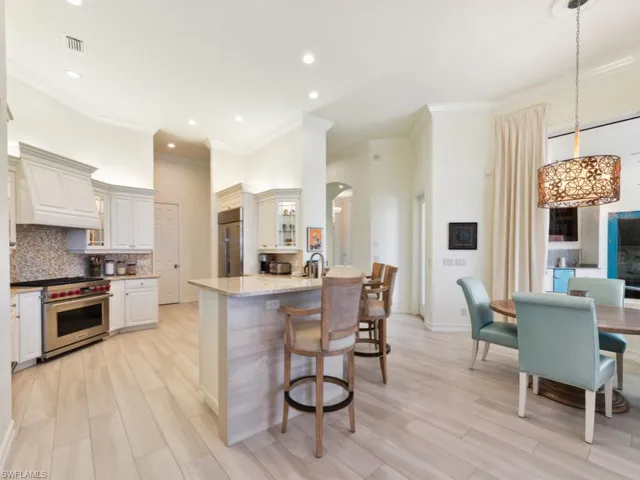 Kitchen featuring premium appliances, premium range hood, crown molding, light stone countertops, and backsplash