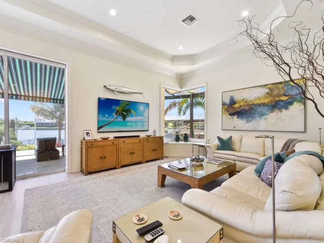 Living room featuring ornamental molding, a wealth of natural light, and a raised ceiling
