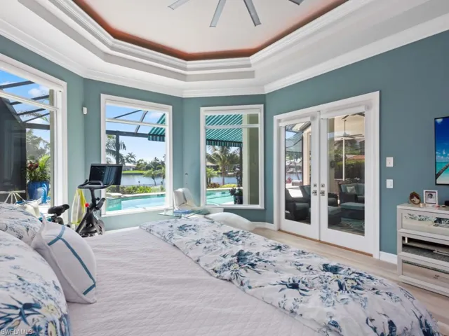 Bedroom with french doors, access to outside, a raised ceiling, and crown molding
