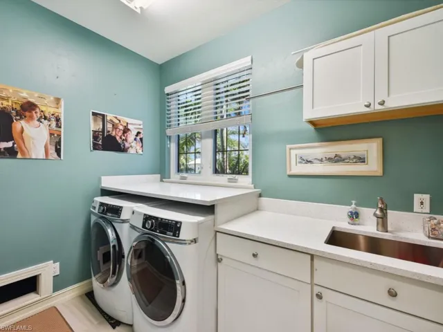 Washroom with washing machine and clothes dryer, sink, and cabinets