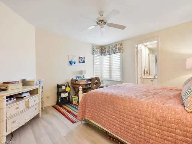 Bedroom with light hardwood / wood-style flooring, ensuite bath, and ceiling fan