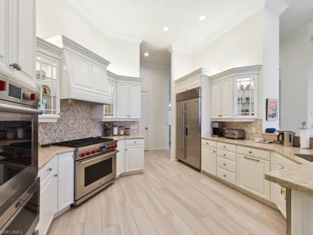 Kitchen featuring decorative backsplash, crown molding, custom exhaust hood, and high end appliances