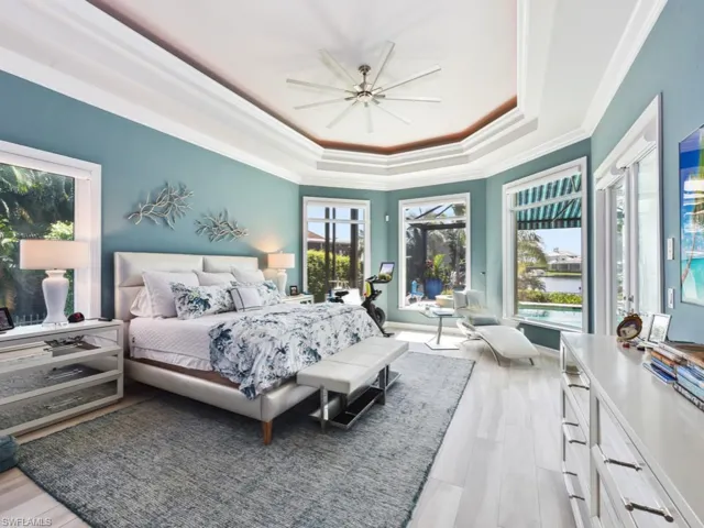 Bedroom featuring multiple windows, ceiling fan, a raised ceiling, and light hardwood / wood-style floors
