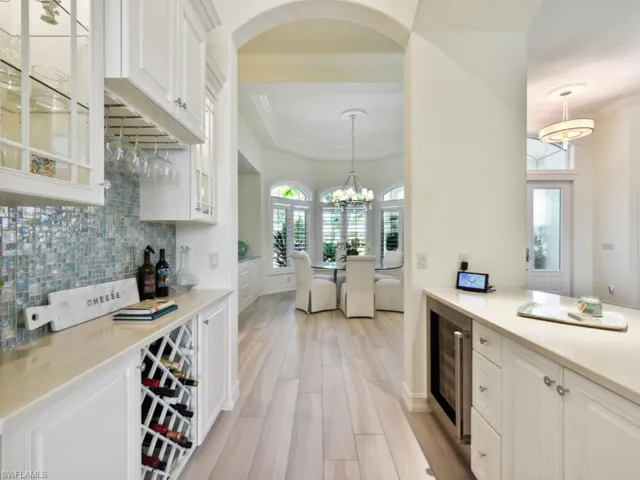 Bar with white cabinets, ornamental molding, wine cooler, light hardwood / wood-style floors, and backsplash