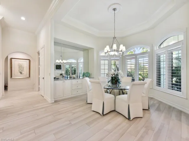 Dining area with a chandelier, a raised ceiling, and light wood-type flooring