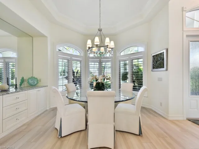 Dining room featuring a chandelier, a raised ceiling, and light wood-type flooring