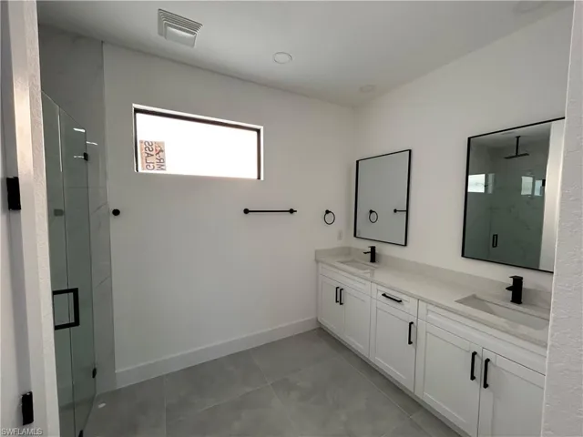 Bathroom featuring tile patterned floors, vanity, and an enclosed shower