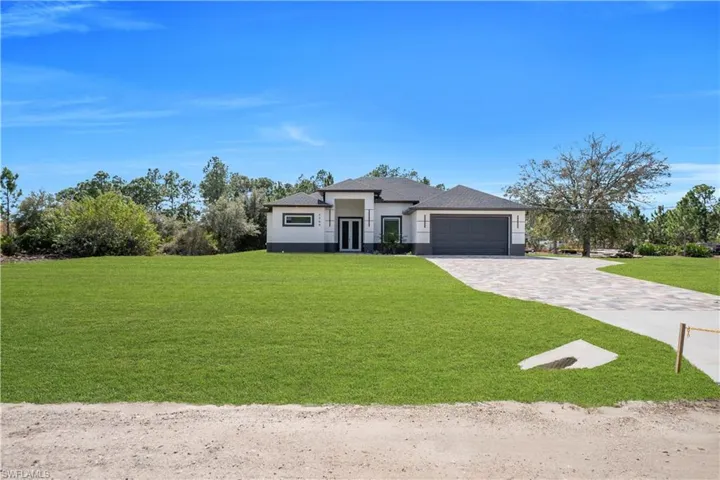 Prairie-style home featuring a front yard, decorative driveway, a garage, and stucco siding