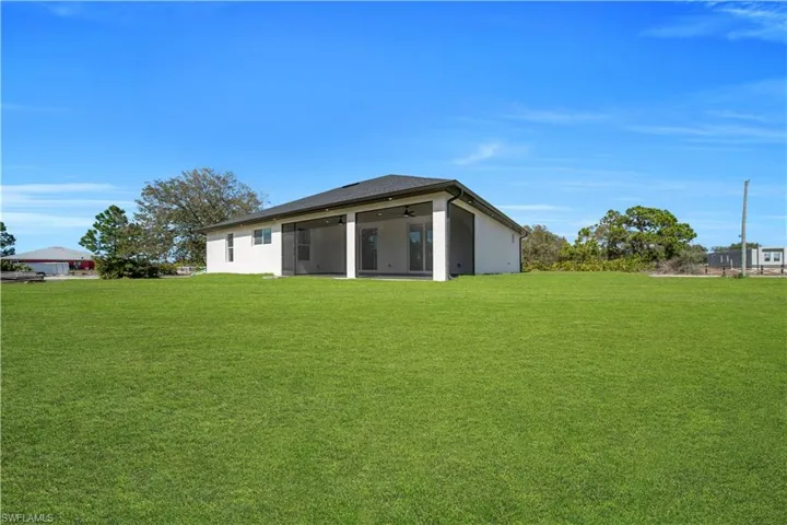 Back of property with a lawn, stucco siding, and a ceiling fan
