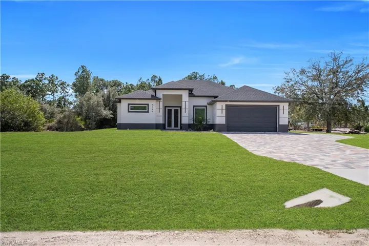Prairie-style home featuring a front lawn, decorative driveway, stucco siding, an attached garage, and french doors