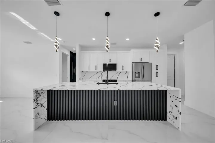 Kitchen with light stone counters, white cabinets, light marble finish floors, and stainless steel appliances