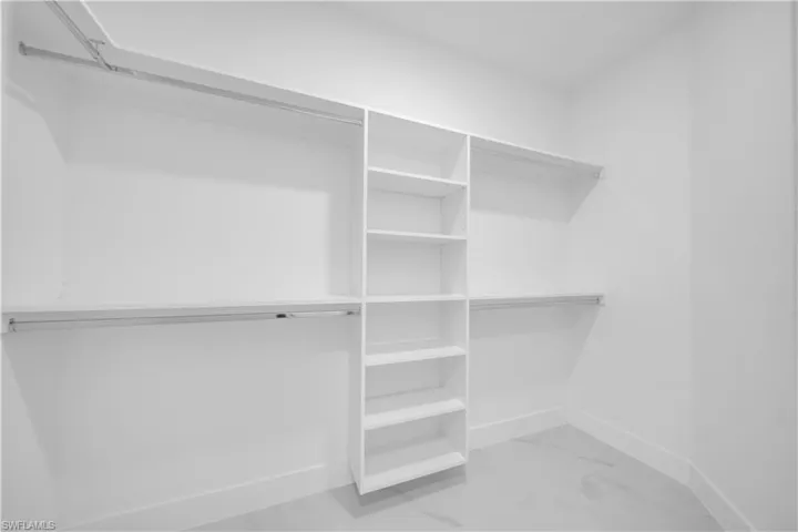 Walk in closet featuring light marble finish flooring