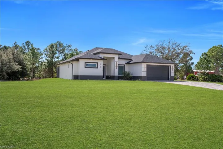 Prairie-style house with a front yard, stucco siding, driveway, and an attached garage