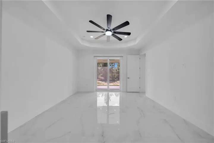 Spare room with ceiling fan, marble tiled flooring, a tray ceiling, and recessed lighting