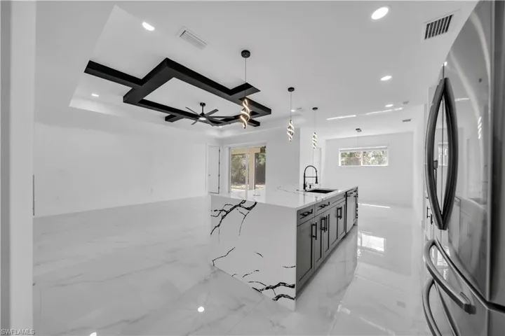 Kitchen with stainless steel appliances, light stone countertops, pendant lighting, open floor plan, and a ceiling fan