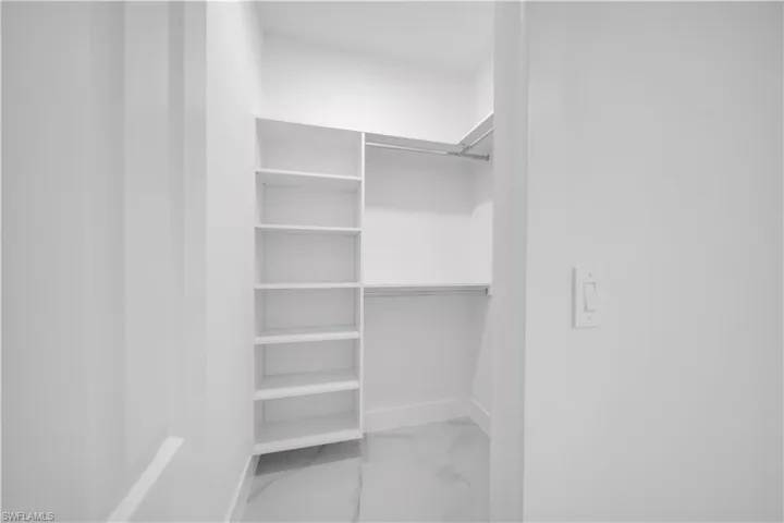 Walk in closet featuring light marble finish floors
