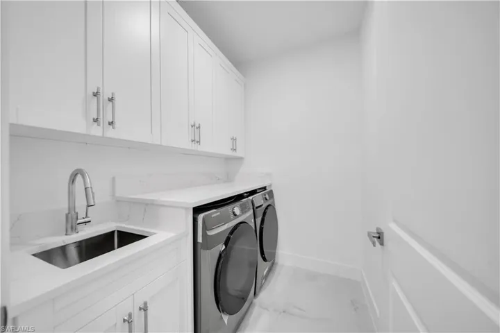 Laundry room featuring cabinet space, independent washer and dryer, and light marble finish flooring