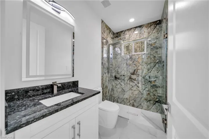 Full bathroom featuring vanity, a marble finish shower, and recessed lighting