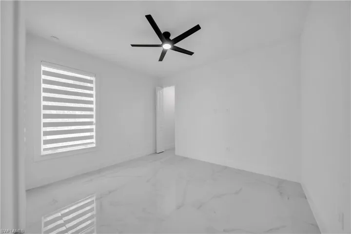 Empty room featuring ceiling fan and marble look tiles