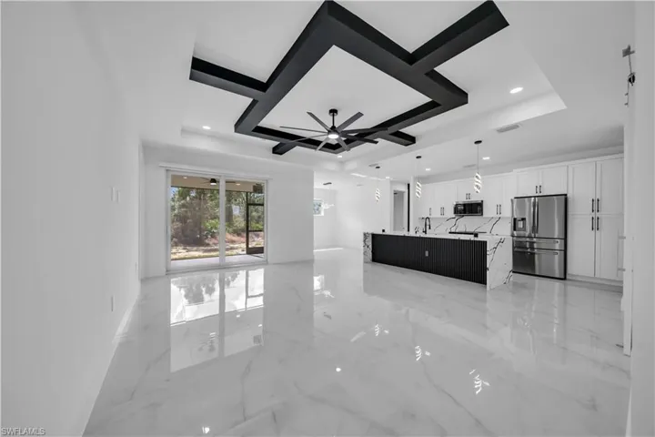 Unfurnished living room with a raised ceiling, a ceiling fan, light marble finish flooring, and recessed lighting
