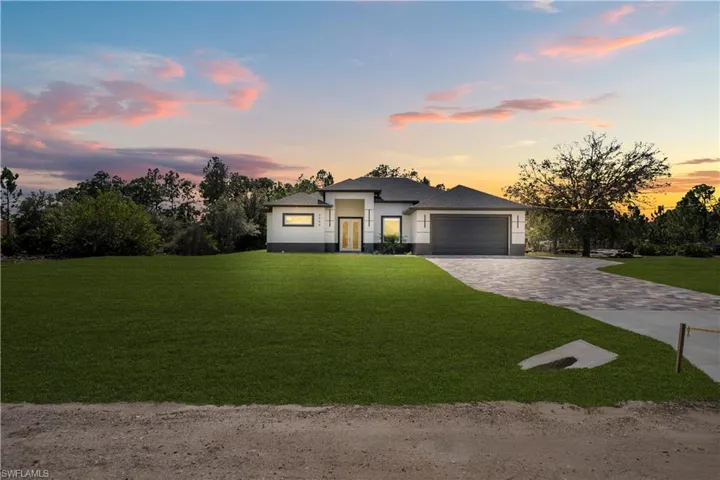 Prairie-style house featuring a yard, decorative driveway, a garage, and stucco siding