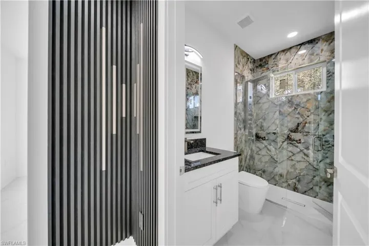 Full bathroom with vanity, a marble finish shower, recessed lighting, and light marble finish floors