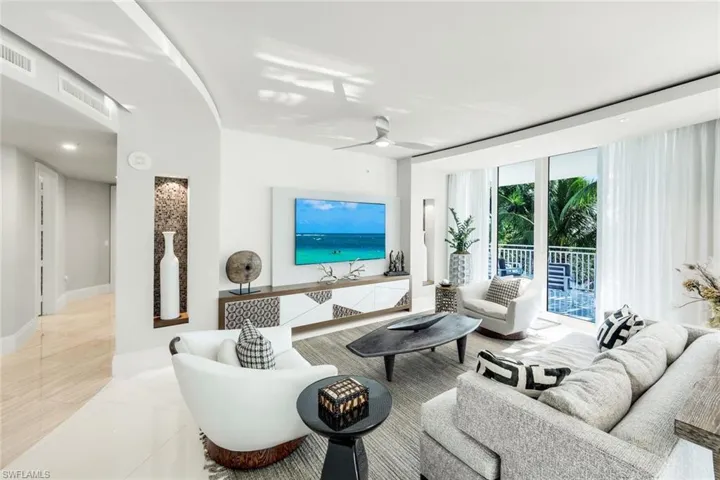 Tiled living area featuring a ceiling fan and expansive windows