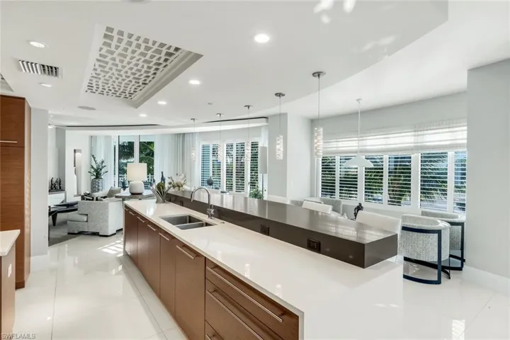 Kitchen with modern cabinets, light stone countertops, pendant lighting, open floor plan, and light tile patterned floors