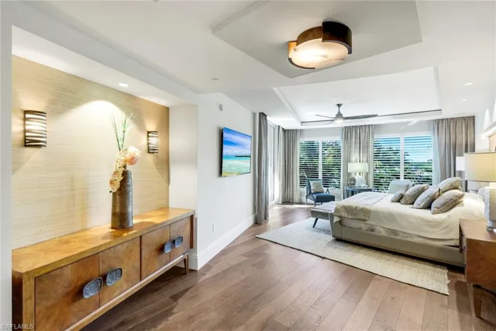 Bedroom with hardwood / wood-style flooring, a ceiling fan, and a raised ceiling