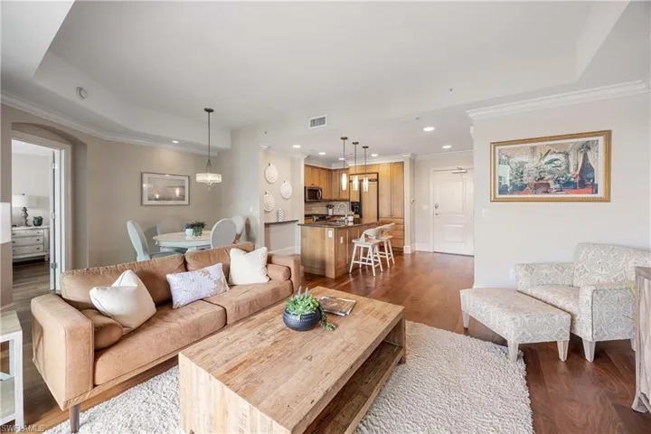 Living room featuring a raised ceiling, crown molding, and dark wood-type flooring