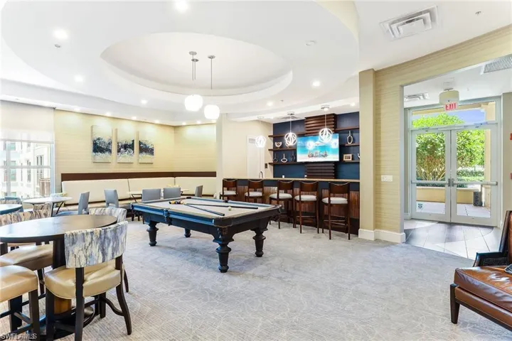 Playroom featuring french doors, billiards, bar, a raised ceiling, and light colored carpet
