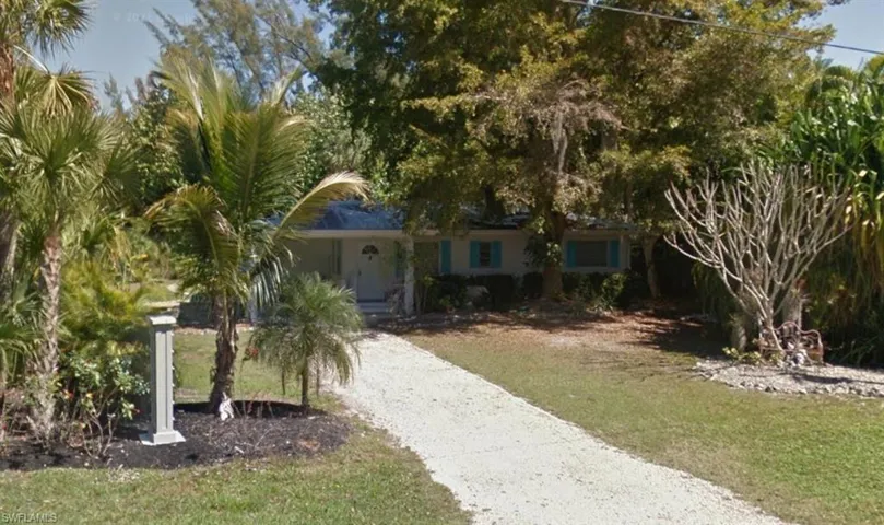 View of property hidden behind natural elements with a front lawn