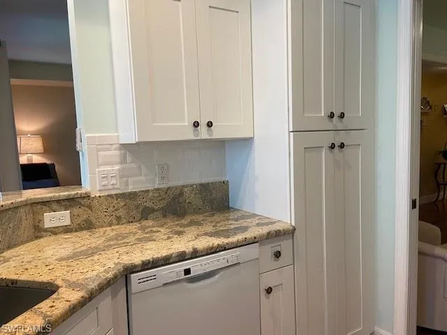 white dishwasher, white cabinetry, and tasteful backsplash