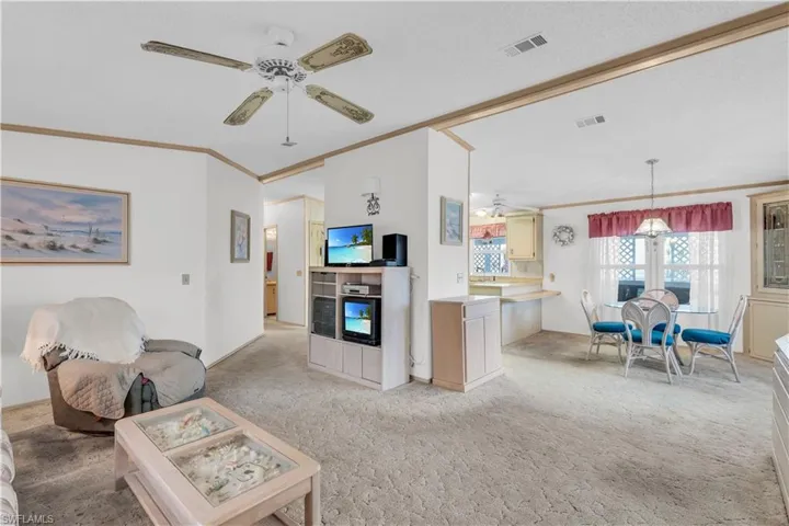 Living room featuring crown molding, light colored carpet, and ceiling fan
