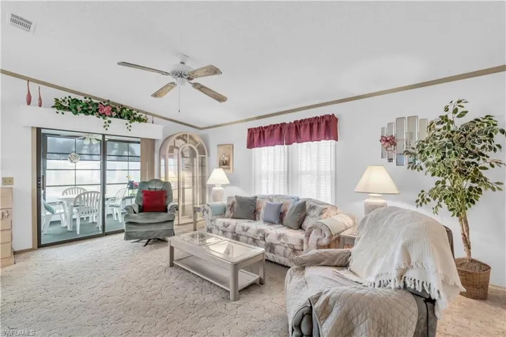 Carpeted living room featuring vaulted ceiling, crown molding, and ceiling fan