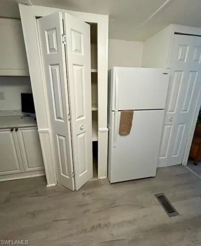 Kitchen with freestanding refrigerator and light wood-style flooring