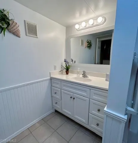 Bathroom featuring vanity, a wainscoted wall, and light tile patterned floors
