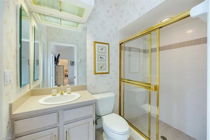 Bathroom with vanity, toilet, and a shower with door