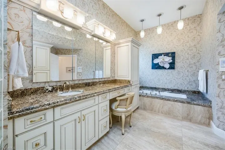 Bathroom featuring vanity and tiled bath