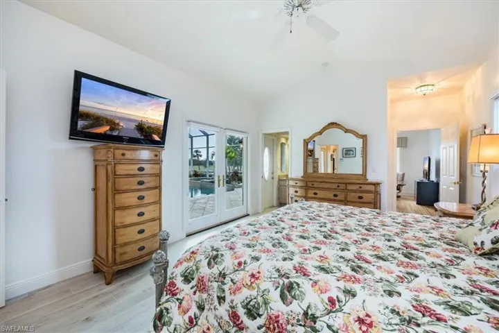 Bedroom with vaulted ceiling, access to exterior, light wood-type flooring, and ceiling fan
