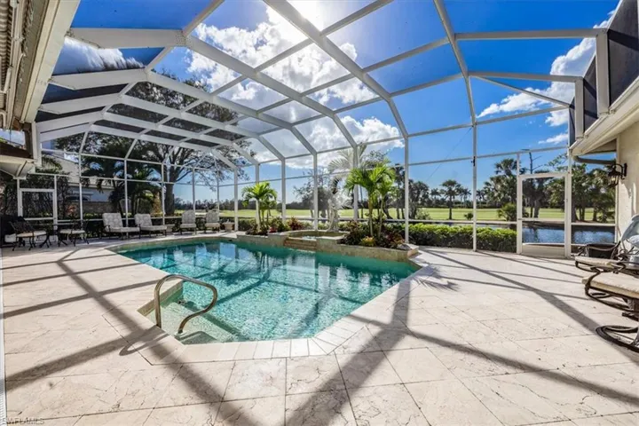 View of pool featuring a patio area and glass enclosure