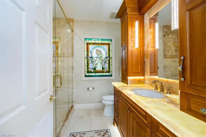 Bathroom with toilet, a shower with shower door, vanity, and tile patterned flooring