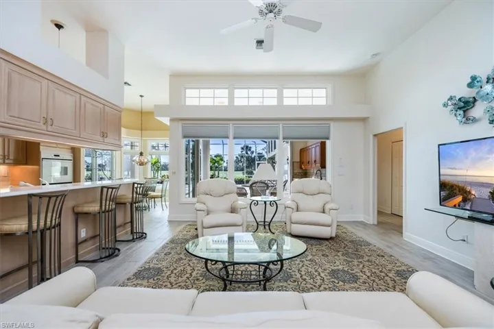 Living room featuring a towering ceiling, light hardwood / wood-style flooring, and ceiling fan with notable chandelier