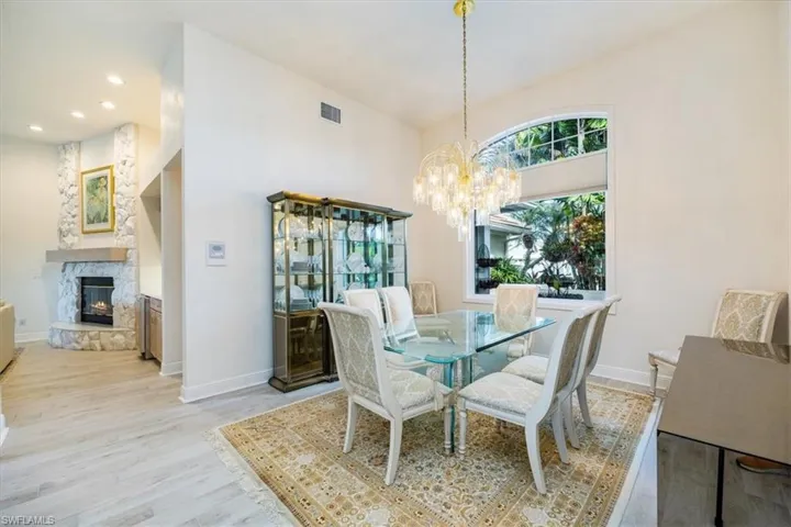 Dining area with an inviting chandelier, a premium fireplace, and light hardwood / wood-style floors