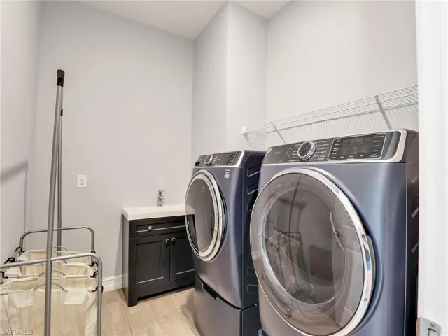 Washroom featuring separate washer and dryer, light hardwood / wood-style flooring, cabinets, and sink