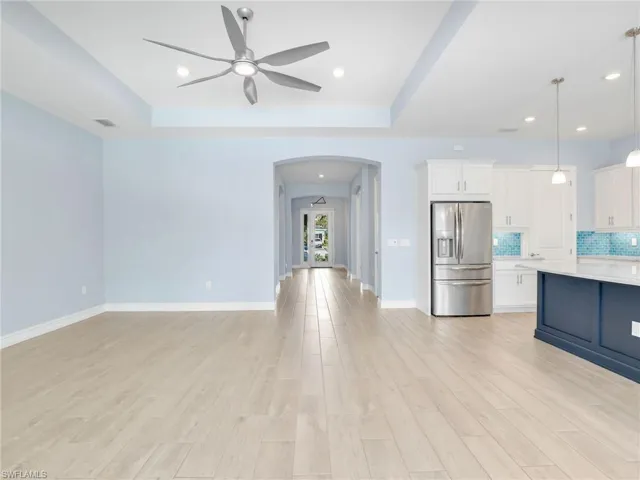 Kitchen with white cabinetry, tasteful backsplash, stainless steel fridge with ice dispenser, light hardwood / wood-style flooring, and decorative light fixtures